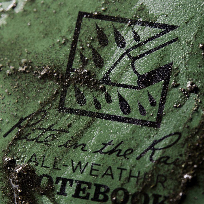 close up of olive green waterproof notebook with dirt on it