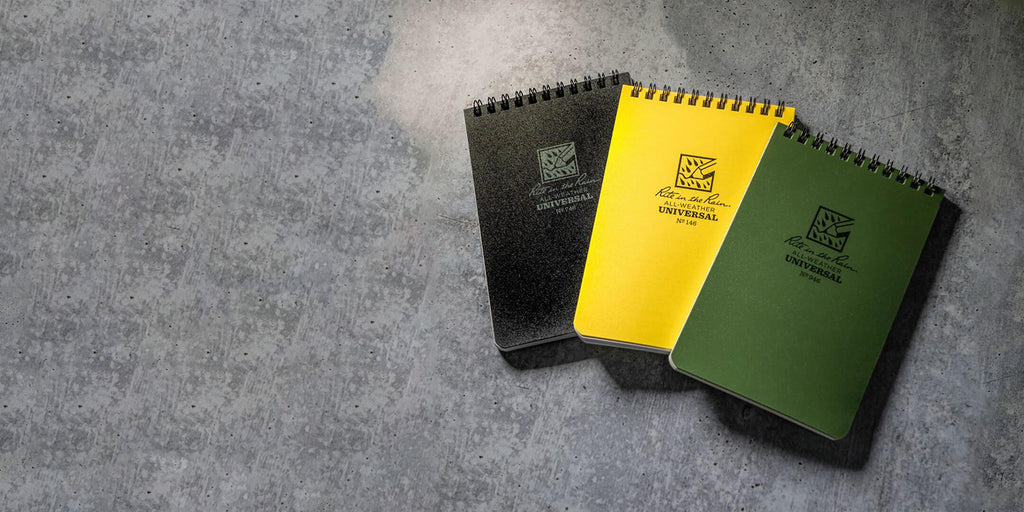 waterproof notebook in black, yellow and green laid out on a grey background
