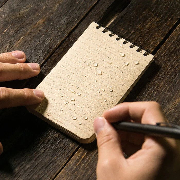 close up of person writing on waterproof pocket notebook